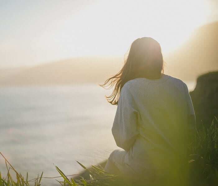 woman sat on a cliff looking out to sea