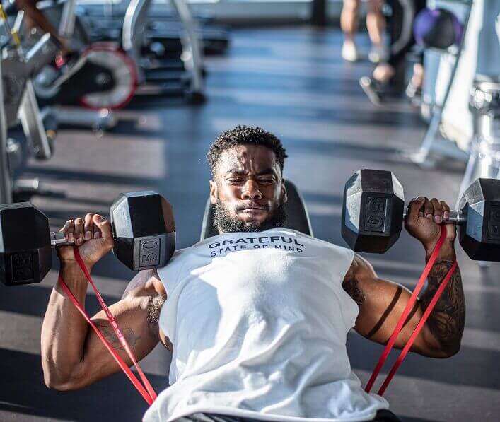 Man in white shirt lifting two dumbbells