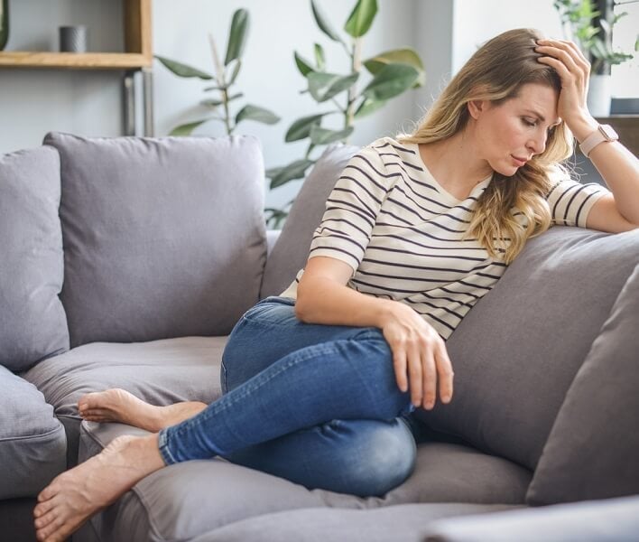 Middle aged woman sitting on the couch (negative emotions)