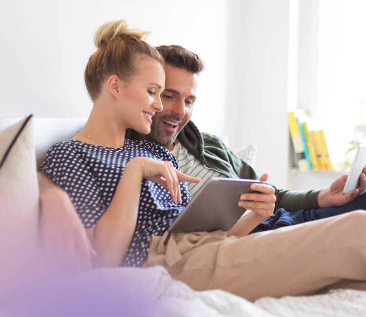 Couple sat on sofa looking at an ipad