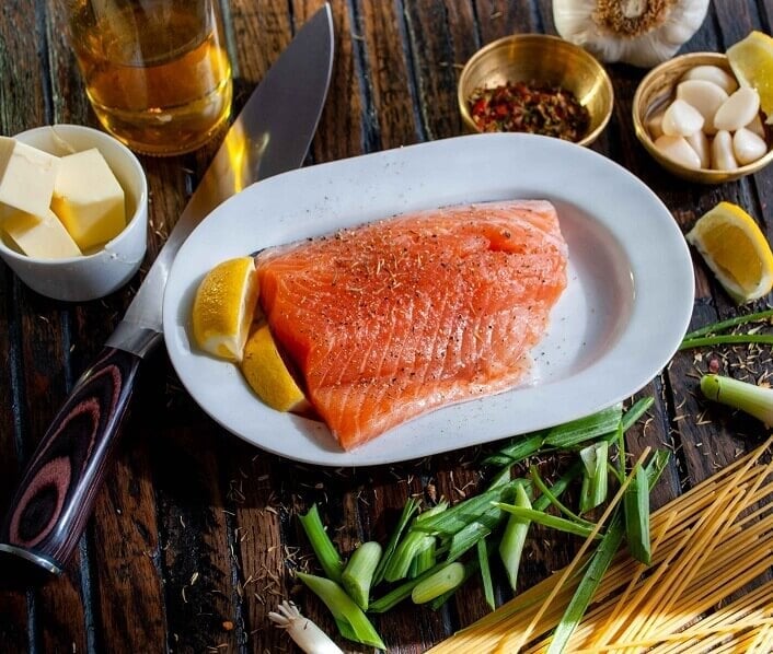 Plate of salmon with vegetables and herbs on the table