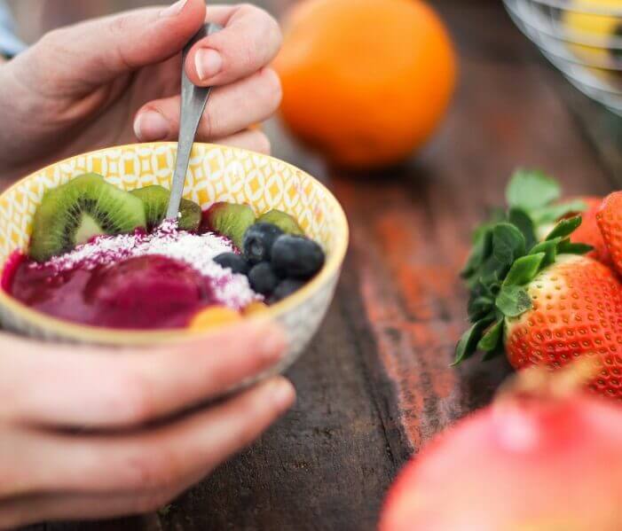 Person eating a bowl of fruit