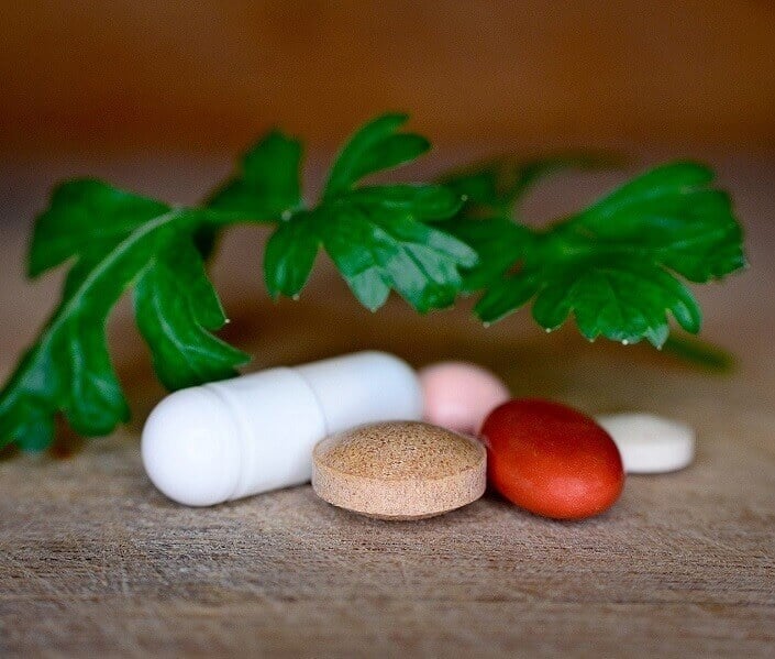 Vitamin supplements laid out on a table with a leaf over them