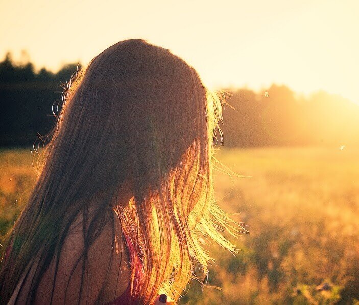 Woman in a field facing into the sunset