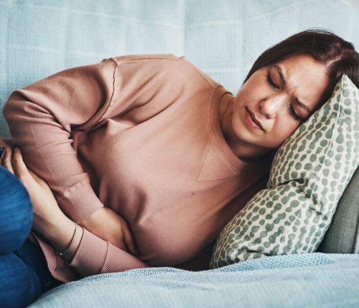 woman on sofa clutching her stomach
