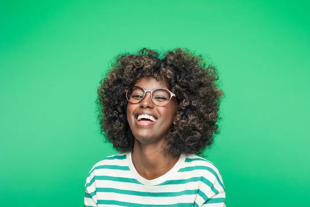 Smiling black woman with glasses, green background