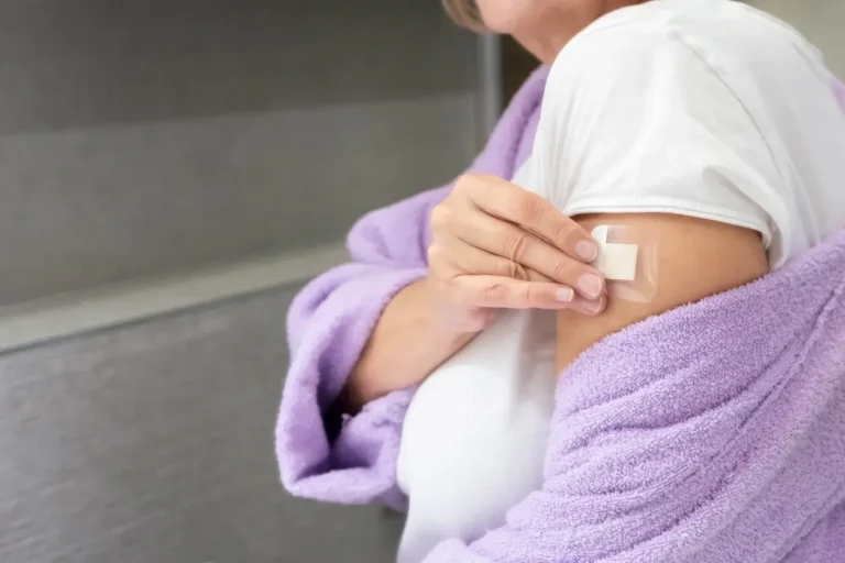 Woman applying hrt patch to her upper arm