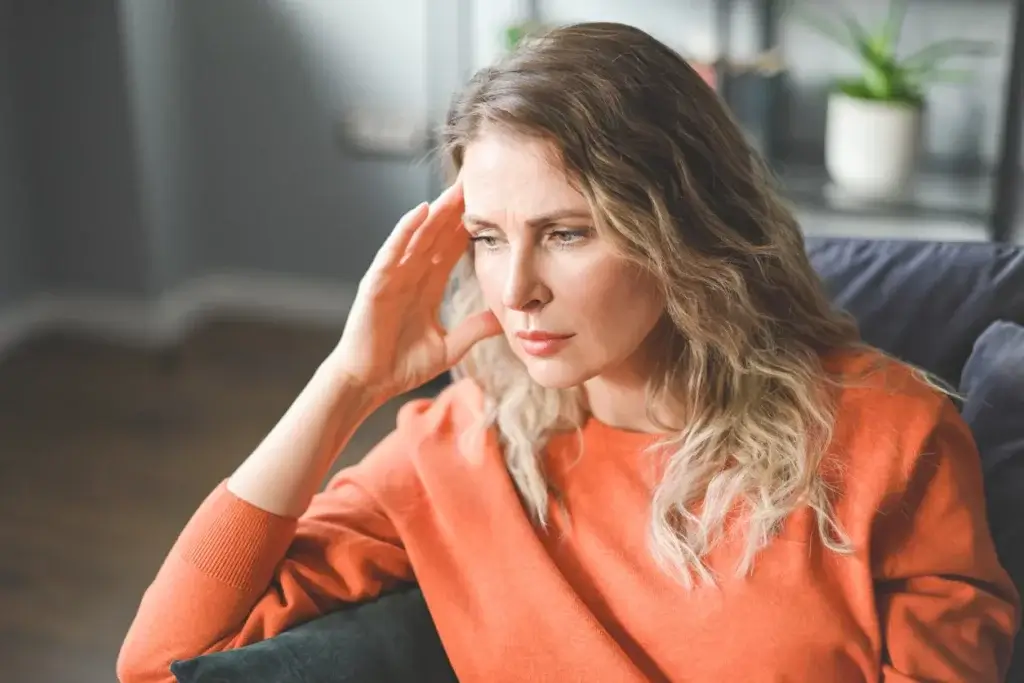 Perimenopausal woman holding her head in hands